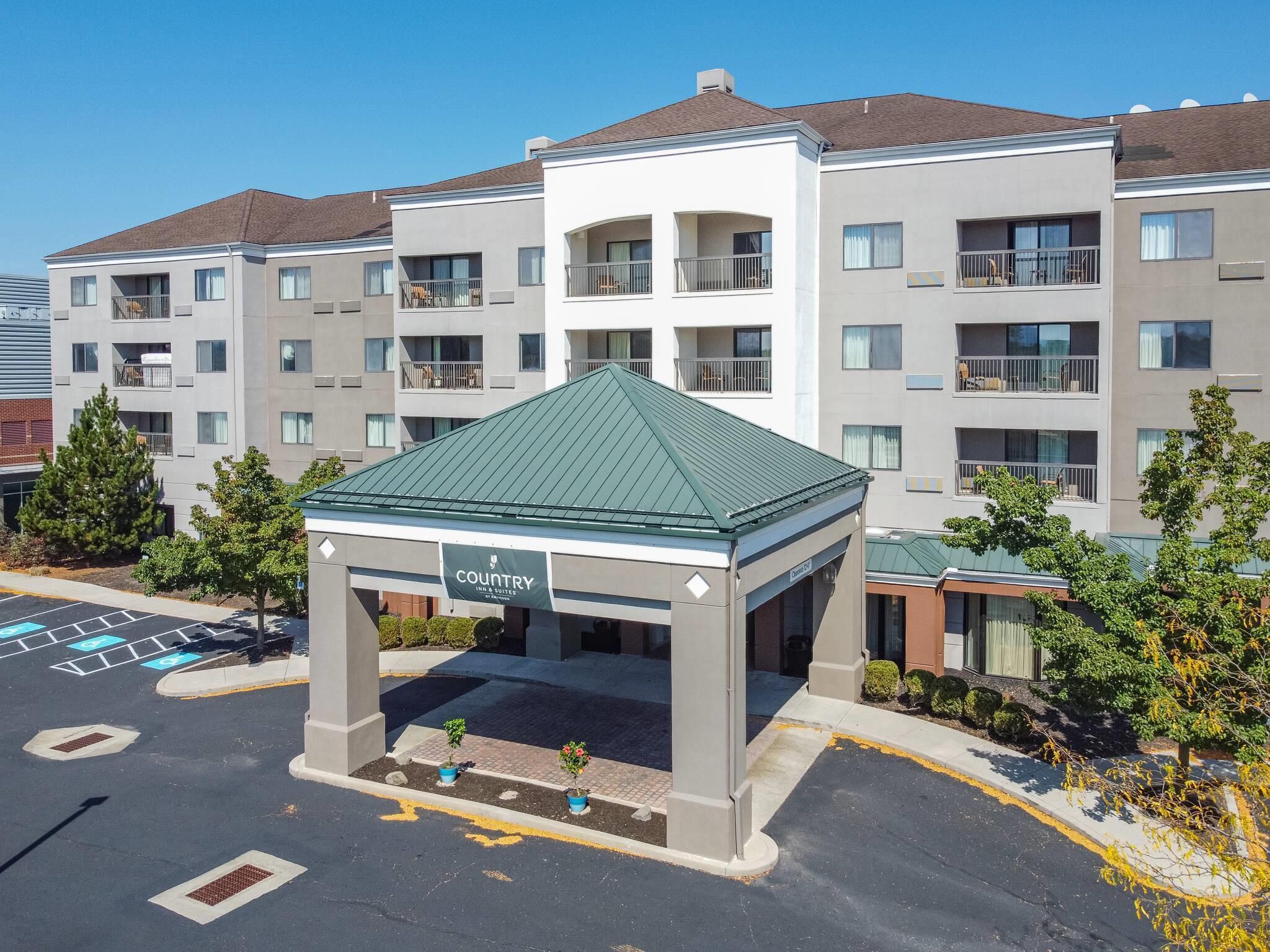 A multi-story hotel with a central courtyard, balconies, and a parking lot.