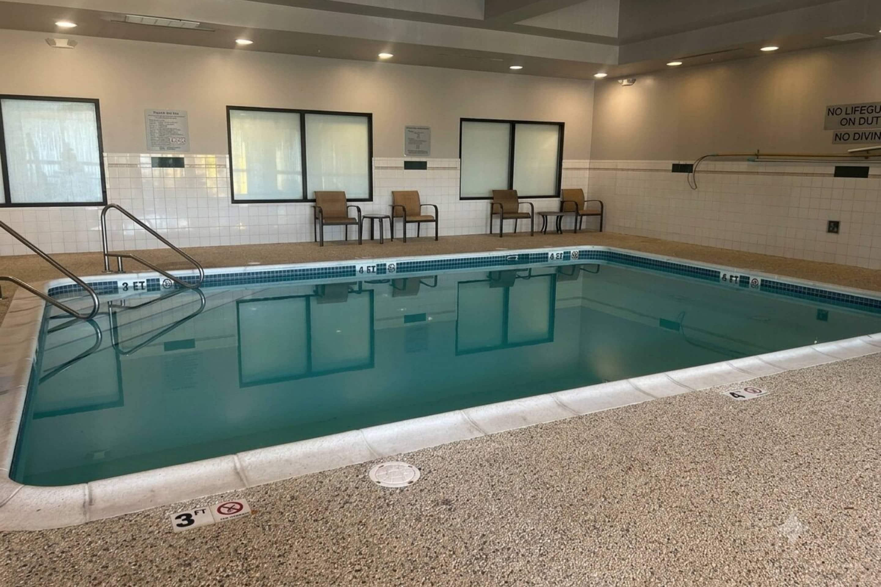 Une piscine intérieure à l’eau claire, avec des repères indiquant la profondeur et un sol carrelé.