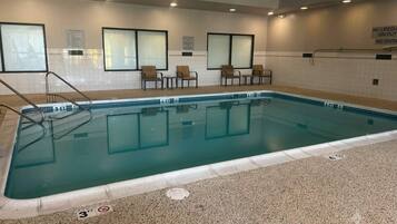 Une piscine intérieure à l’eau claire, avec des repères indiquant la profondeur et un sol carrelé.