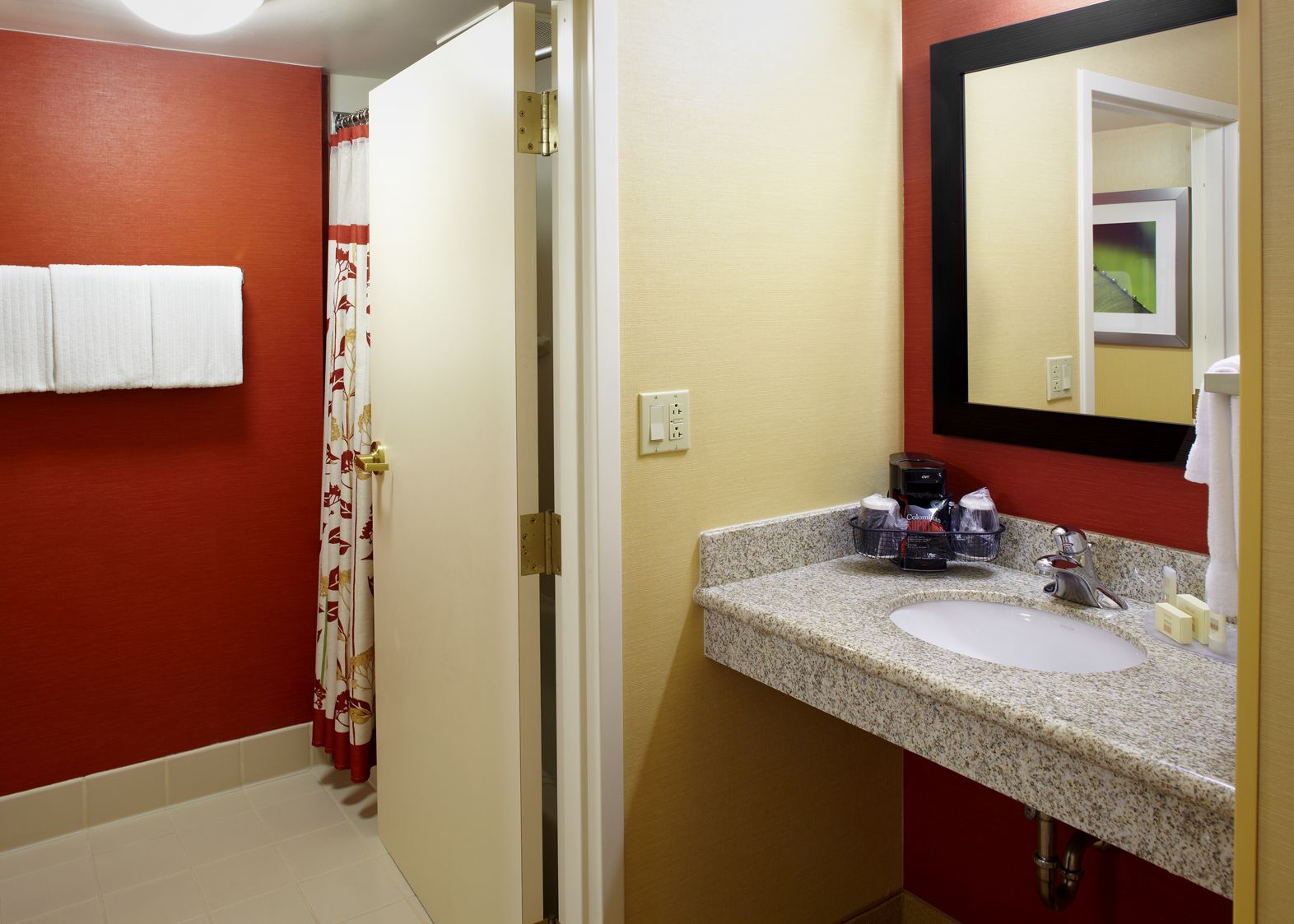 A bathroom with a sink, mirror, and red walls.