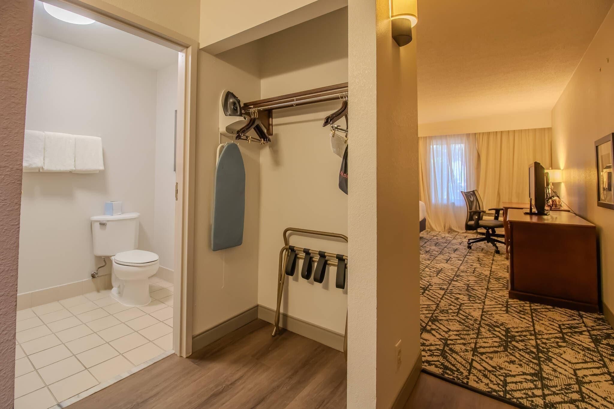Un baño de hotel con inodoro, toallero y cortina de ducha.