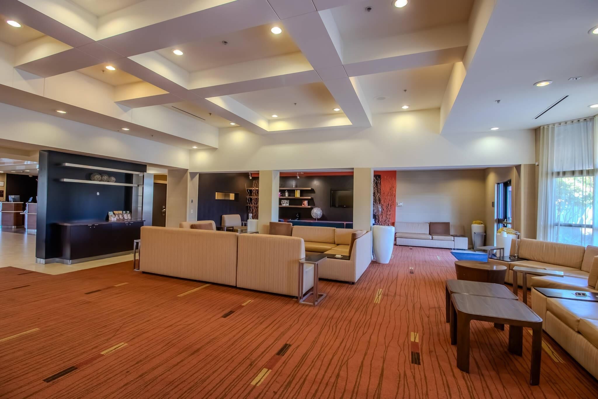 Eine geräumige Lobby mit Empfangsschalter, Sofas, einem Couchtisch und einem großen Fenster.