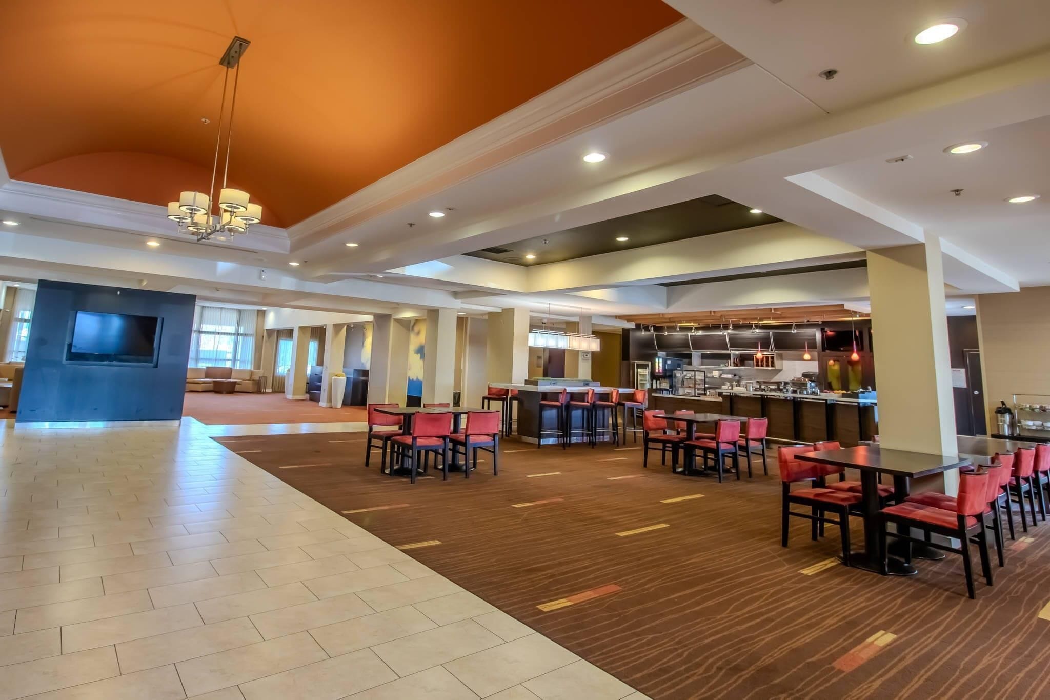 A spacious lobby with a bar area, seating arrangements, and a television screen.