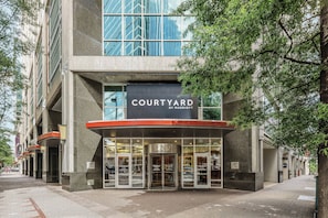A modern building with a sign reading "COURTYARD BY MARRIOTT" and a revolving door entrance.