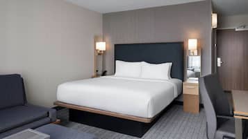 Una habitación de hotel con cama, escritorio, silla y sofá.