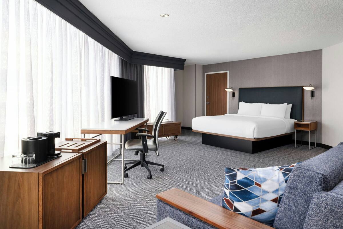 Une chambre d’hôtel comprenant un lit, un bureau avec une chaise, une télévision et un canapé.