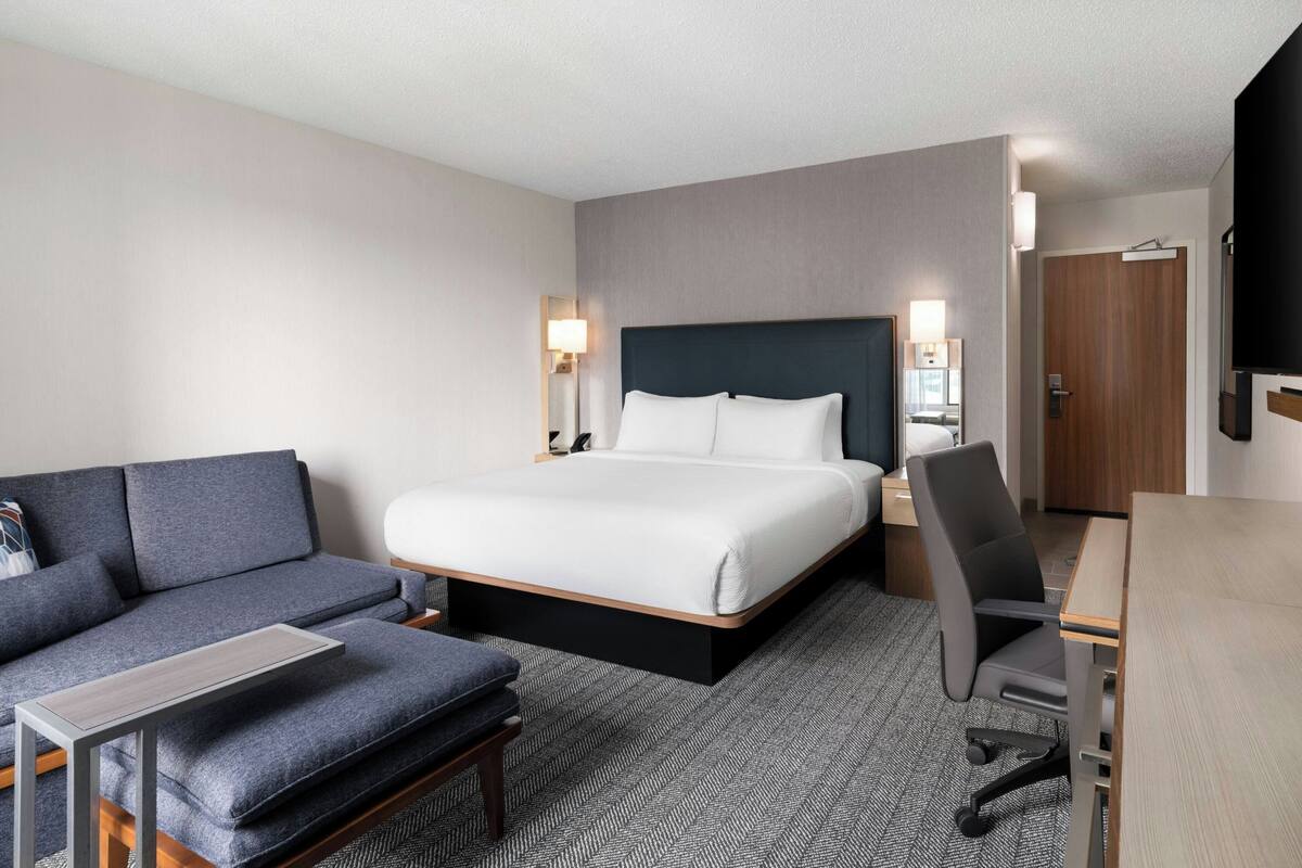 Une chambre d’hôtel avec un lit, un canapé, un bureau et une chaise.