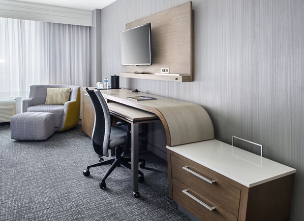 A hotel room with a desk, chair, and a flat-screen TV mounted on the wall. - Courtyard by Marriott Charlotte City Center (Charlotte)