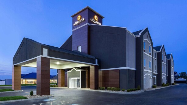 Un hotel con una entrada destacada, un área cubierta y un cartel con el nombre del hotel.