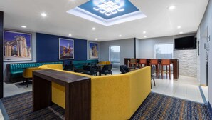Un moderno vestíbulo de hotel con mostrador de recepción central, zona de estar y una pared de acento de piedra.