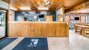 A reception area with a wooden reception desk, a clock, and a sign indicating amenities. - Knights Inn New Florence (New Florence)