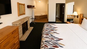 A hotel room with a bed, a wooden dresser, a flat-screen TV, a fireplace, a bathroom with a bathtub, and a hallway leading to another room. - Knights Inn New Florence (New Florence)