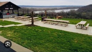 A picnic area with benches and a food station, overlooking a body of water and hills. - Knights Inn New Florence (New Florence)
