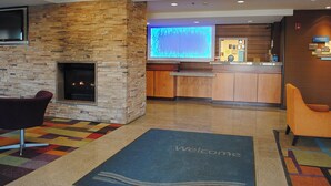 A lobby with a stone fireplace, a reception desk, and a 'Welcome' mat.