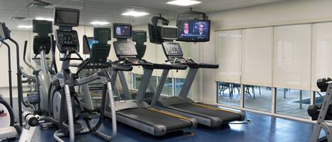 Une salle de sport équipée de tapis de course, de vélos elliptiques et de matériel de musculation.