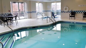 An indoor swimming pool with clear glass walls, a lifeguard chair, and a sign indicating no diving.