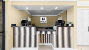 Una taquilla amb un cartell de 'Quality by Choice Hotels', un televisor amb marc negre i una planta en test.
