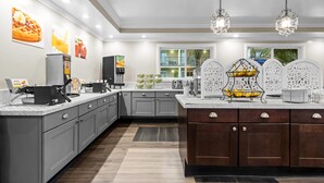 Een moderne keuken met grijze kastjes, een houten keukeneiland, een pannenkoekenstation en decoratieve muurdecoratie.