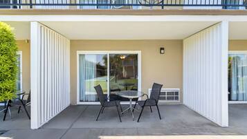 A covered patio with a table and chairs, a potted plant, and a view of the street.
