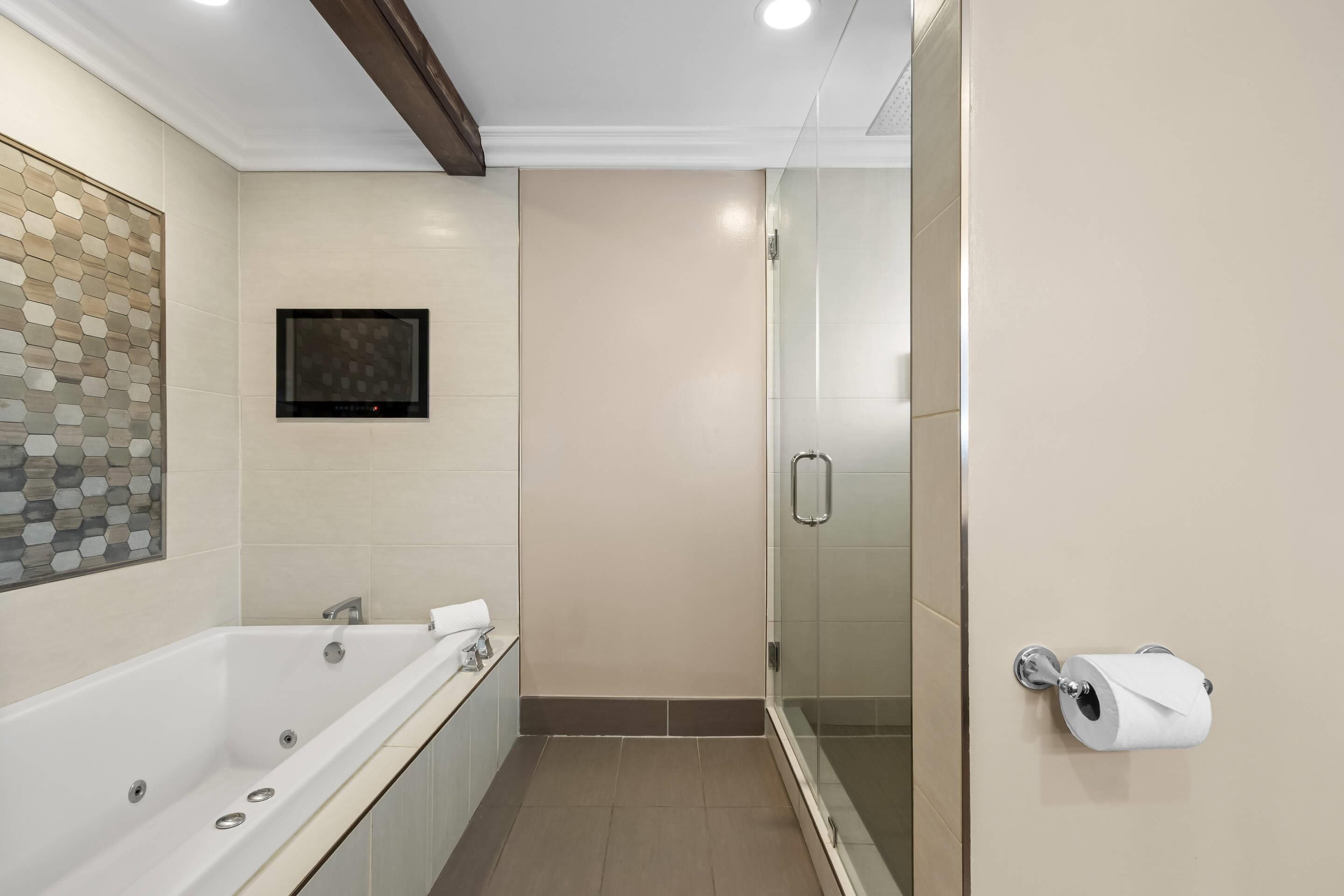 Un baño moderno con bañera, dispensador de papel higiénico y cabina de ducha de vidrio.