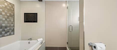 Un baño moderno con bañera, dispensador de papel higiénico y cabina de ducha de vidrio.