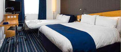 A hotel room with two beds, a desk with a computer, a television, and a window with curtains.