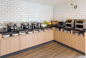 A modern kitchen with white subway tiles, stainless steel appliances, and wooden cabinets. - Holiday Inn Express Southampton - West by IHG (Southampton)