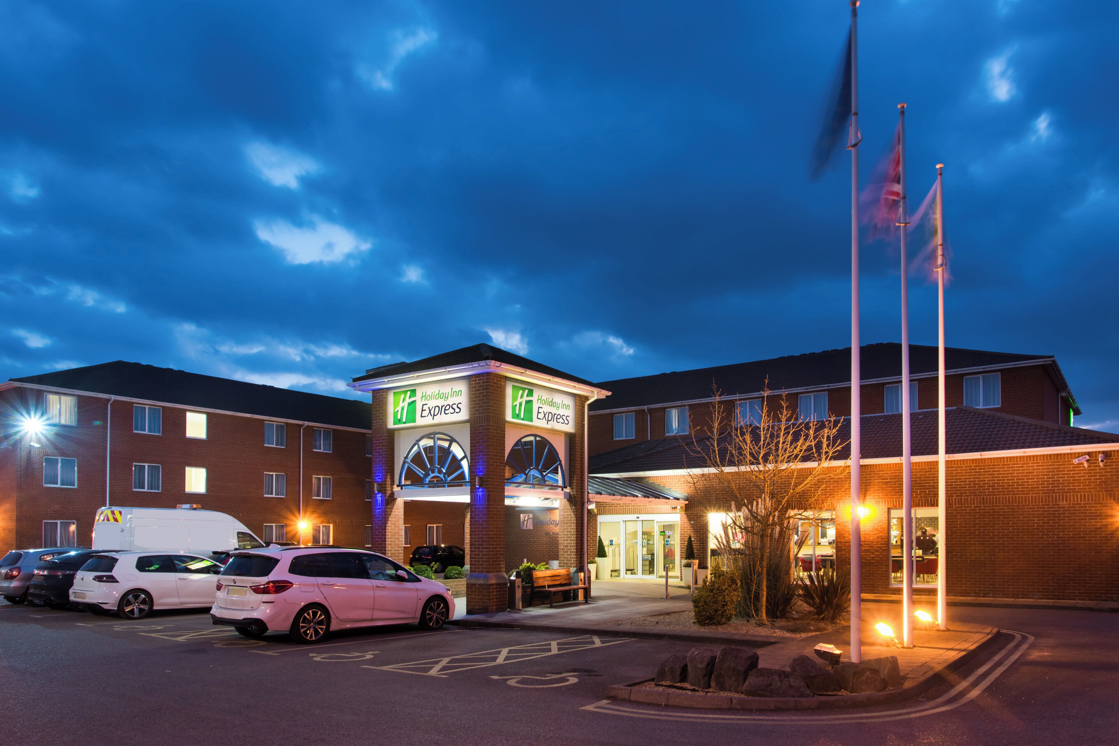 A Holiday Inn Express hotel with a parking lot, a gated entrance, and a flagpole.