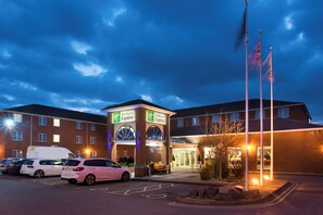 Un hôtel Holiday Inn Express doté d’un parking, d’une entrée sécurisée et d’un mât pour drapeau.