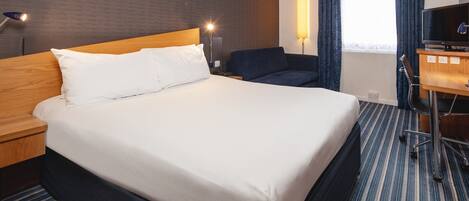 Une chambre d’hôtel avec un grand lit, un bureau avec un ordinateur, une chaise et un téléviseur.