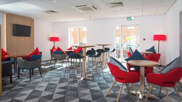 Un espace de détente moderne offrant de nombreuses options d’assises, notamment des tables et des chaises, ainsi qu’un sol à motifs.
