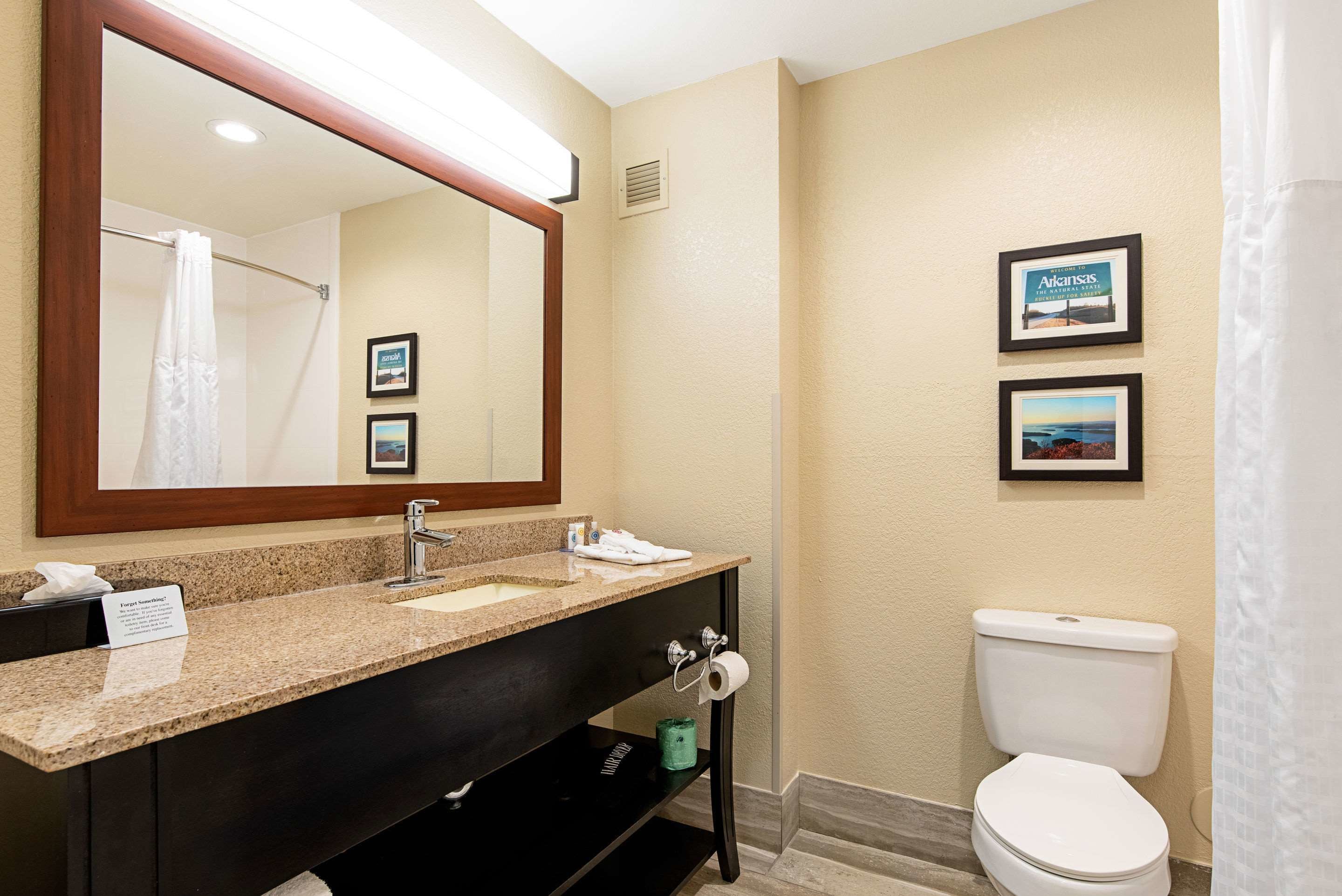 Un baño con lavabo, espejo, inodoro y fotografías enmarcadas en la pared.