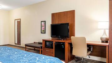Ein Hotelzimmer mit einem Bett, einem Schreibtisch mit Computer, einem Fernseher, einer Mikrowelle und einem Sessel.