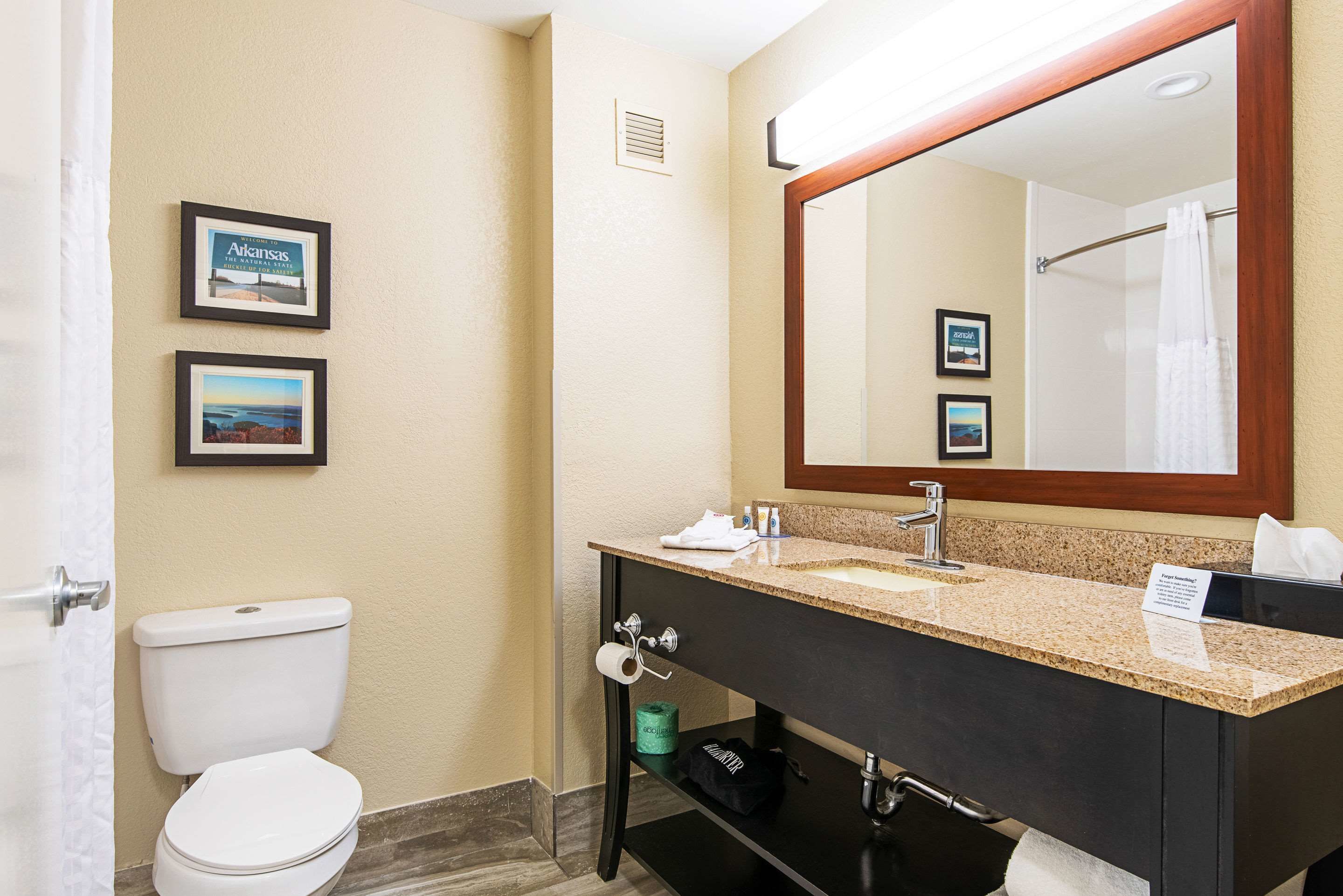 Ein Badezimmer mit Toilette, Waschbecken, Spiegel und gerahmten Bildern an der Wand.