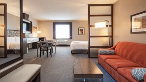 Una habitación de hotel con una cama, un escritorio, una silla, un sofá y un espejo grande.