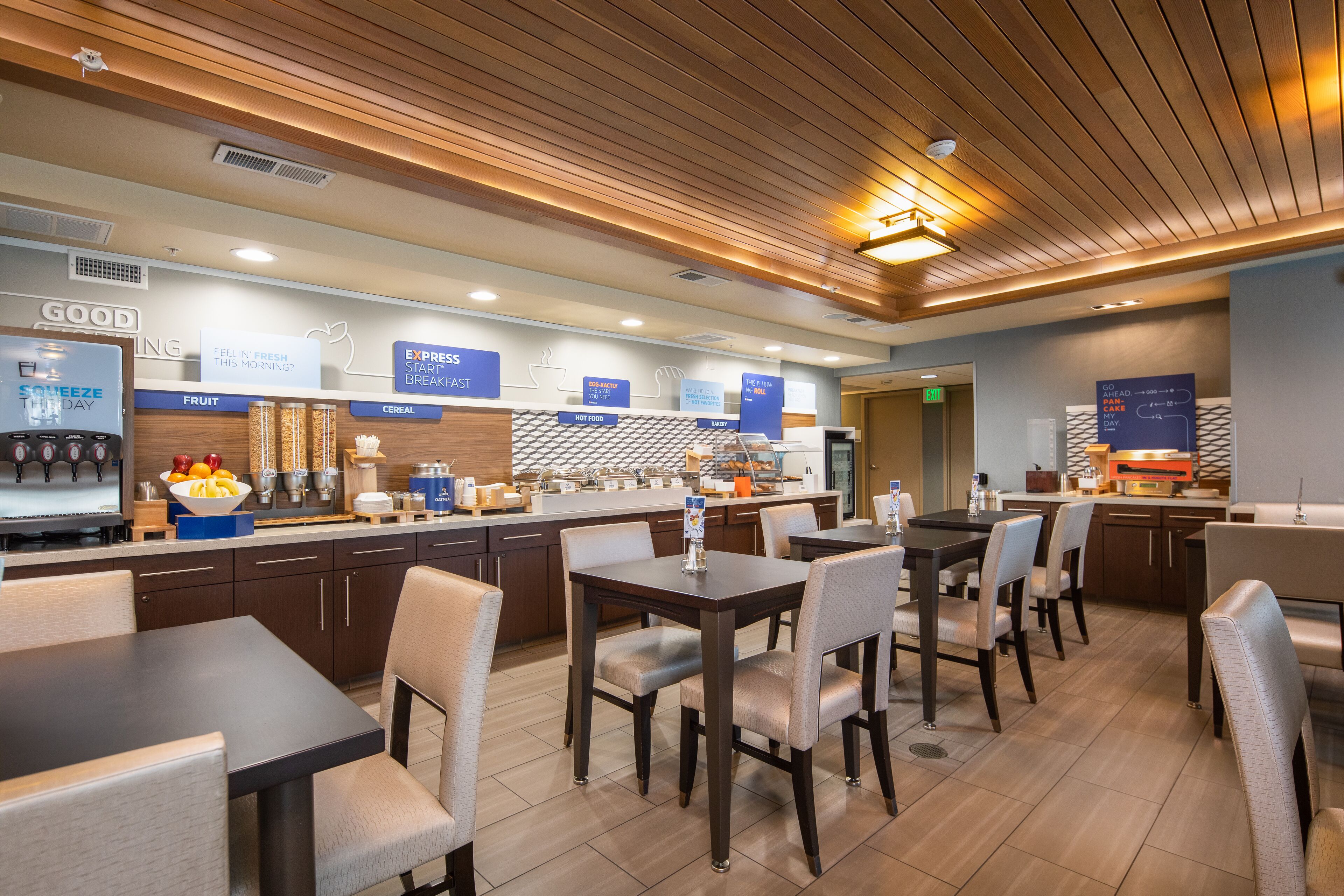 A modern breakfast bar with a variety of food and beverage options, including a coffee machine and a fruit display.