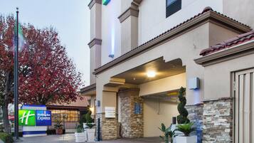 A Holiday Inn Express building with a clear entrance, a parking sign, and a stone facade.