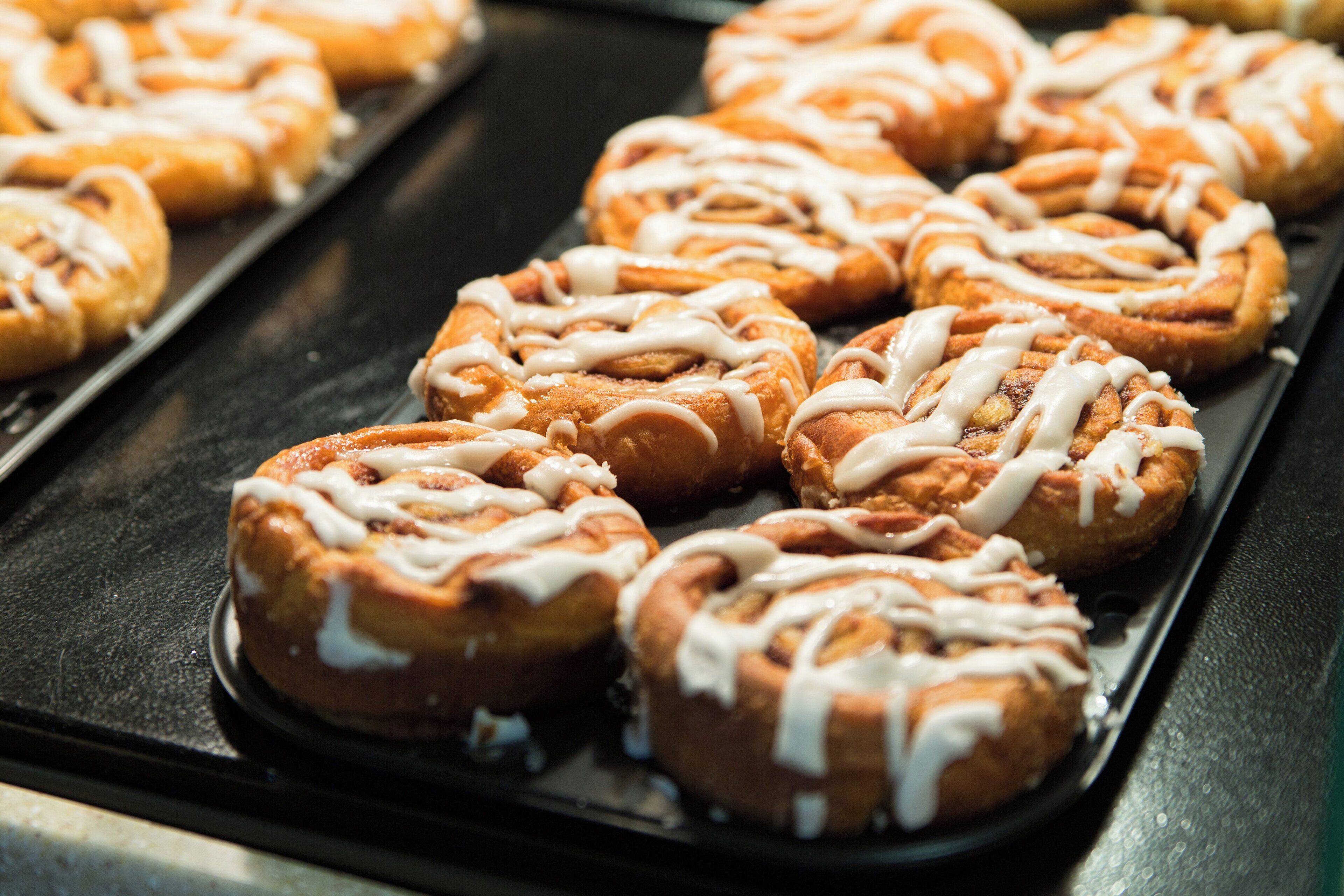 A tray of freshly baked cinnamon rolls with icing.