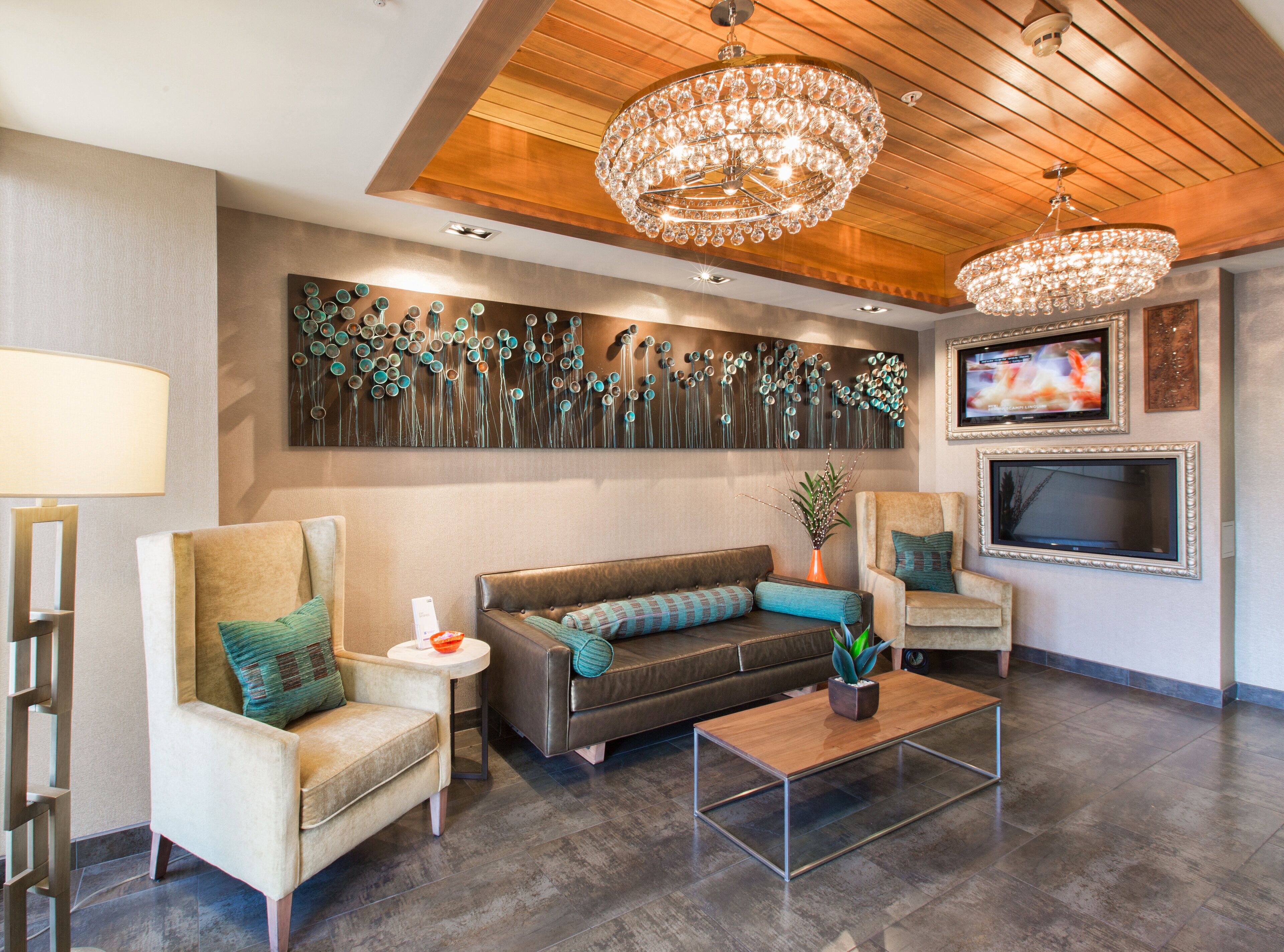 Uma sala de estar moderna com teto de madeira, um lustre grande, TV fixada na parede e uma obra de arte abstrata decorativa.