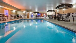 A swimming pool with lounge chairs and umbrellas, surrounded by a checkered wall and a tiled floor. - Hampton Inn Mitchell (Mitchell)