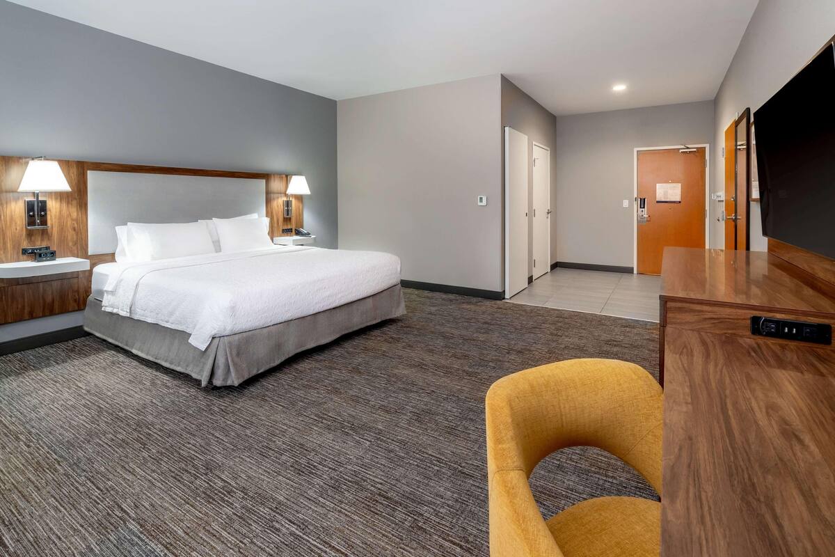 A hotel room with a bed, bedside lamps, a desk, and a chair.