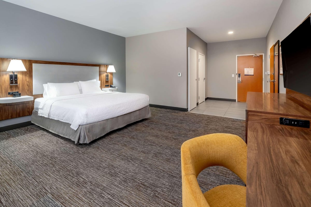 A hotel room with a bed, bedside lamps, a desk, and a chair.