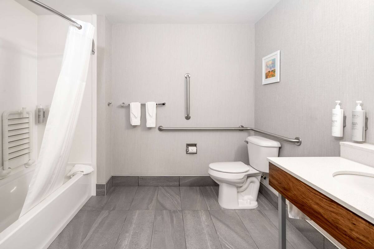 A modern bathroom with a bathtub, toilet, and vanity.