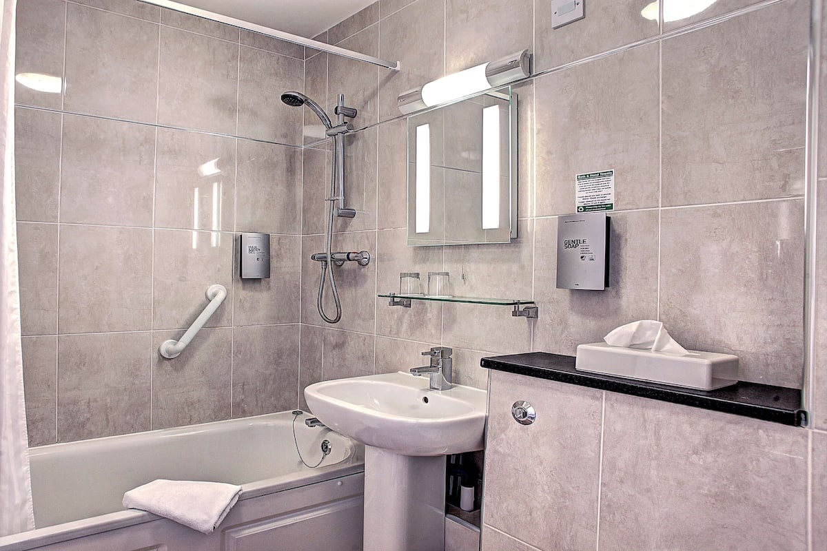 Une salle de bain moderne avec une baignoire, un lavabo, un miroir et une douche.