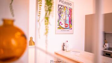 Habitación de hotel con diseño minimalista, que presenta un cuadro grande de Picasso en la pared, un minibar y vistas de la ciudad.