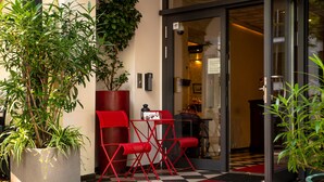 A hotel entrance with a checkered floor, red chairs, a red mat, and potted plants. - Boutique Hotel Kerlin (Berlin)