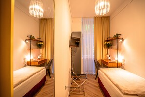Habitación de hotel con dos camas, un escritorio, una silla, un televisor y un espejo.