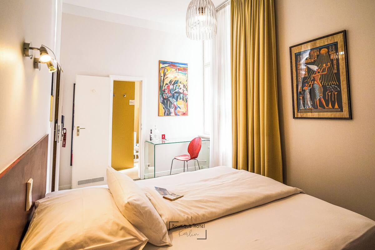 Ein Hotelzimmer mit Bett, Schreibtisch, Stuhl und Bildern an den Wänden.