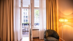 A hotel room with a view of the street, a chair, a lamp, and a radiator. - Boutique Hotel Kerlin (Berlin)