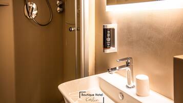 A bathroom with a white sink, a mirror, and a shower.